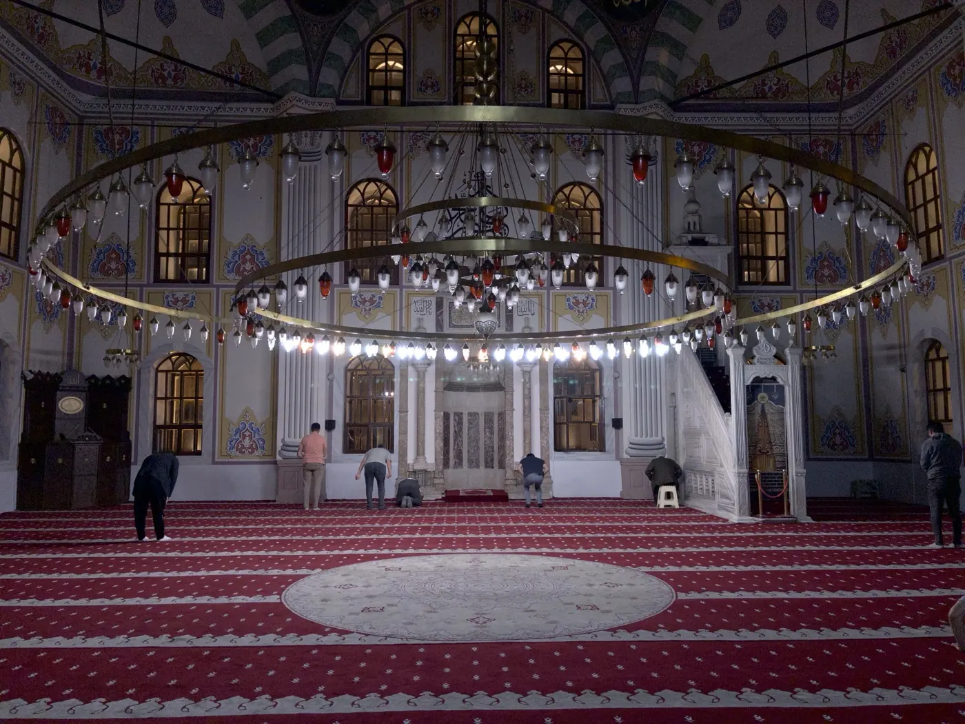 The interior of Bayezid Mosque, a ring chandelier above a red carpet