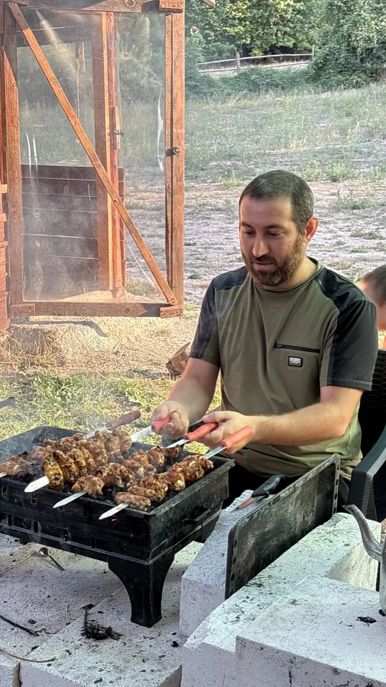 Skewers cooking on a grill with a person tending them